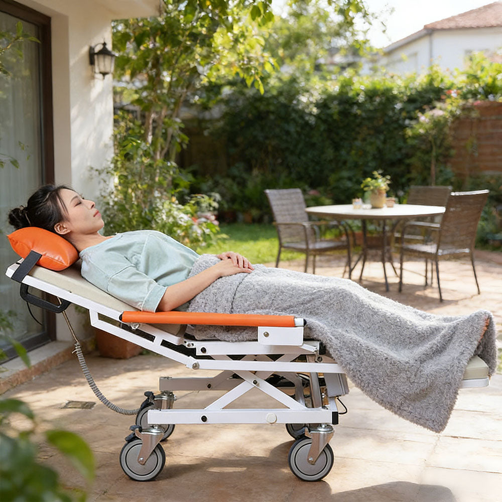 Woman asleep under a grey blanket on the fully reclined transfer machine on a sunny garden terrace
